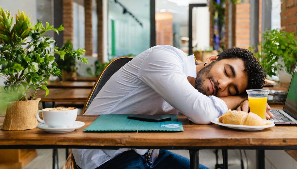 Homem de costas dorminado em sua mesa de trabalho durante o almoço