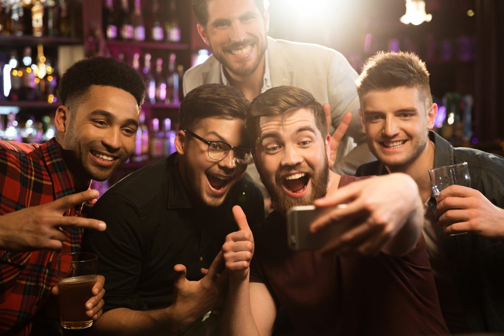 Amigos do sexo masculino felizes tirando selfie e bebendo cerveja